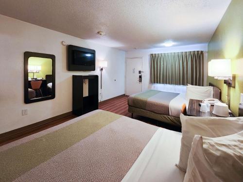 a hotel room with two beds and a mirror at Motel 6-Baytown, TX - Baytown East in Baytown