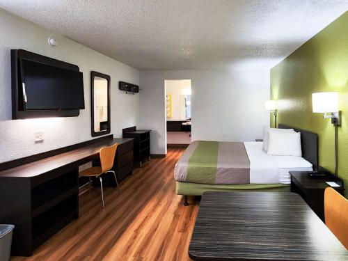 a hotel room with a bed and a desk and a tv at Motel 6-Baytown, TX - Baytown East in Baytown