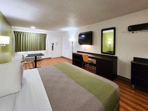 a hotel room with a bed and a desk and a mirror at Motel 6-Baytown, TX - Baytown East in Baytown