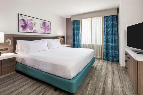 a hotel room with a bed and a flat screen tv at Hilton Garden Inn Lafayette/Cajundome in Lafayette