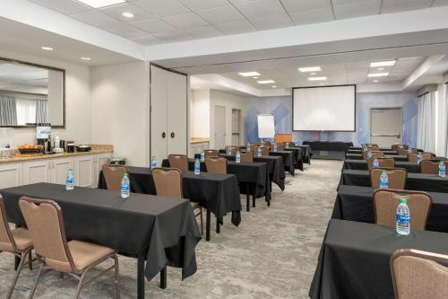 a conference room with tables and chairs and a screen at Hilton Garden Inn Lafayette/Cajundome in Lafayette