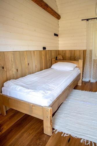 a bed in a room with wooden walls and wood floors at Haanjamehe Taluhotell in Haanja