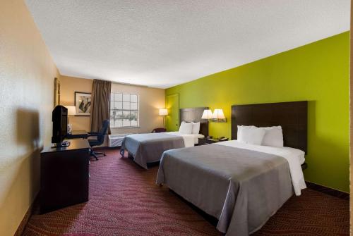 a hotel room with two beds and a green wall at Quality Inn Airport in Woodson Terrace