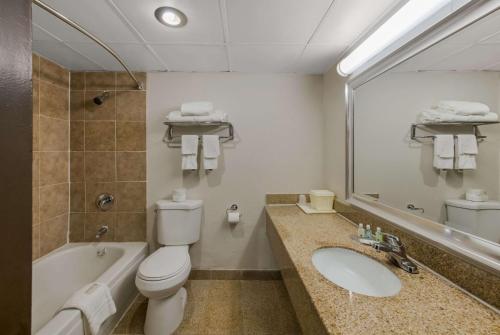 a bathroom with a toilet and a sink and a tub at Quality Inn Airport in Woodson Terrace