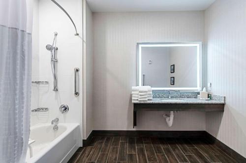 La salle de bains est pourvue d'une baignoire, d'un lavabo et d'un miroir. dans l'établissement Comfort Suites Grove City - Columbus South, à Grove City