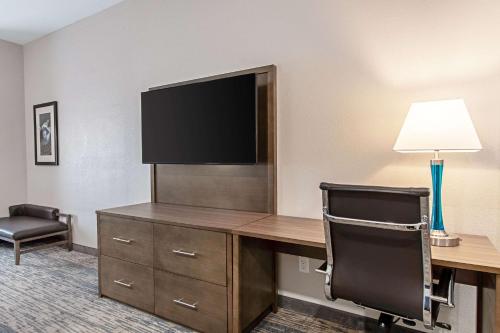 a hotel room with a desk with a television and a chair at Comfort Suites Grove City - Columbus South in Grove City