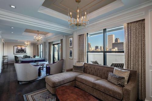 a living room with a couch and a view of the city at Higgins Hotel, Official Hotel of The National WWII Museum, Curio Collection by Hilton in New Orleans