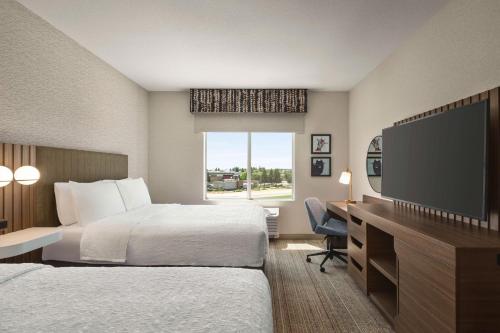 a hotel room with two beds and a flat screen tv at Hampton Inn Stockton, Ca in Stockton