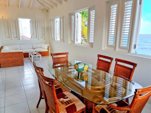 uma sala de jantar com uma mesa de vidro e cadeiras em Beautiful Seaside 2BR Apartments em Christ Church