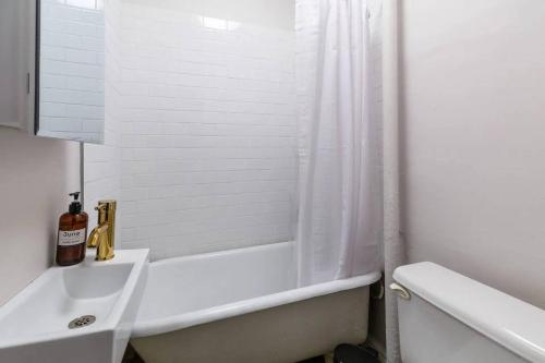 Baño blanco con bañera y lavamanos en Lovely Studio Apt in NYC!, en Nueva York