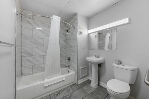 a bathroom with a shower and a toilet and a sink at Budget Inn-Norfolk, VA - Oceanview in Norfolk