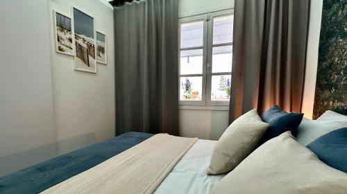 Un dormitorio con una cama con almohadas azules y una ventana en Costa Adeje - Amazing Ocean And Teide View - Fast WiFi, Air Con en Adeje