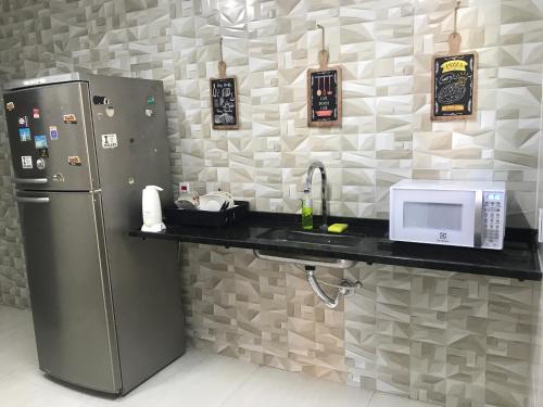 eine Küche mit einem Kühlschrank und einer Mikrowelle auf der Theke in der Unterkunft Pousada Dourados de Itaúna in Saquarema