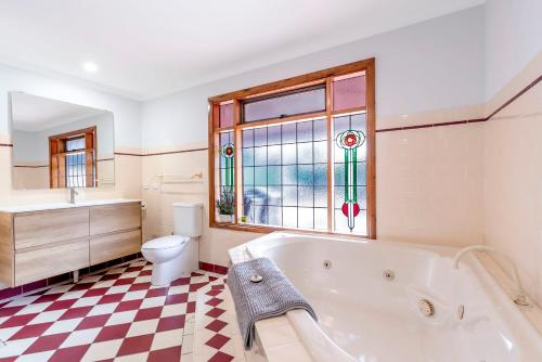 ein Bad mit einer Badewanne, einem WC und einem Fenster in der Unterkunft Welcoming Ambiant 3BR Abode in Tanunda