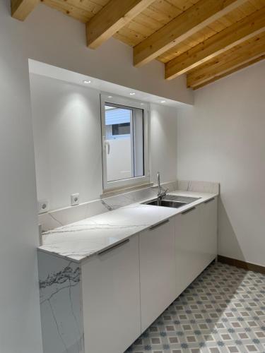 uma cozinha branca com um lavatório e uma janela em THE ORANGE TREE HOUSES - Terraço by Live and Stay em Abrantes