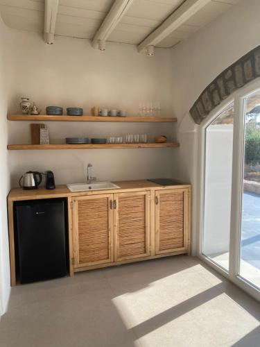 a kitchen with wooden cabinets and a sink and a window at Nerea Sunset View Apartment in Agia Irini Paros