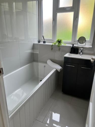 a white bathroom with a tub and a sink at 2 bedroom with garden- Wembley in Preston