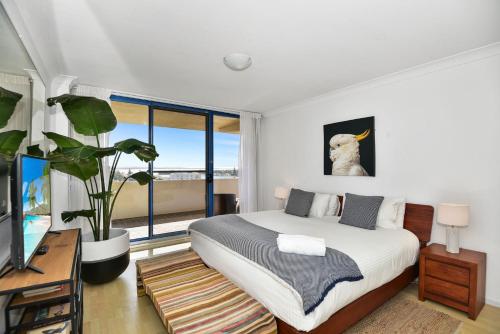 Un dormitorio con una cama y una ventana grande. en Freddie's at St Tropez, en The Entrance