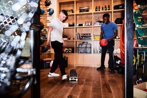two men standing in a room with a skateboard on the floor at The Junto Hotel in Columbus
