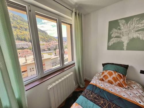 a bedroom with a bed and two large windows at La Capucine - Lumineux avec balcon et parking in Saint-Claude