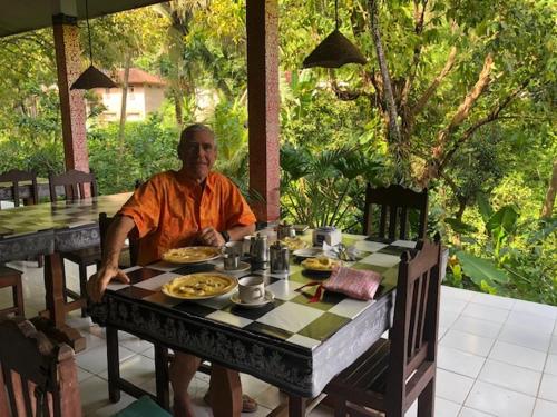a man sitting at a table with food on it at Pondok Wisata Grya Sari in Banjar