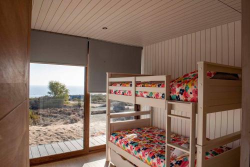 two bunk beds in a room with a window at Preciosa casa para disfrutar en familia CASA REWE in Los Vilos