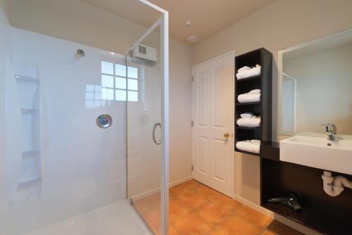 a bathroom with a shower and a sink and a mirror at Lobster Inn Motel in Kaikoura