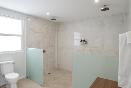 ein weißes Bad mit einem WC und einem Fenster in der Unterkunft Villa Aura 15-25mins from Airport & Attractions in Laborie