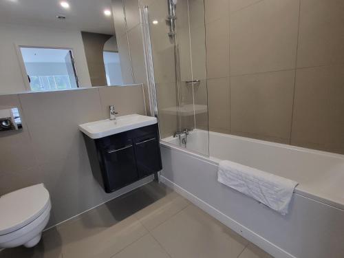 a bathroom with a sink and a toilet and a bath tub at Vetrelax Basildon City Apartment in Basildon