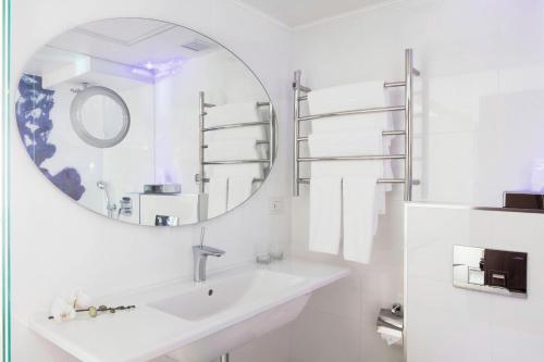 ein weißes Badezimmer mit einem Waschbecken und einem Spiegel in der Unterkunft Renaissance Tel Aviv Hotel in Tel Aviv
