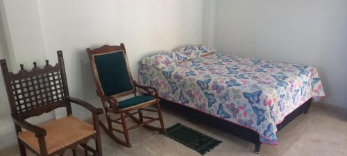 a bedroom with a bed and two wooden chairs at Casa de campo para 10 personas in Ibagué