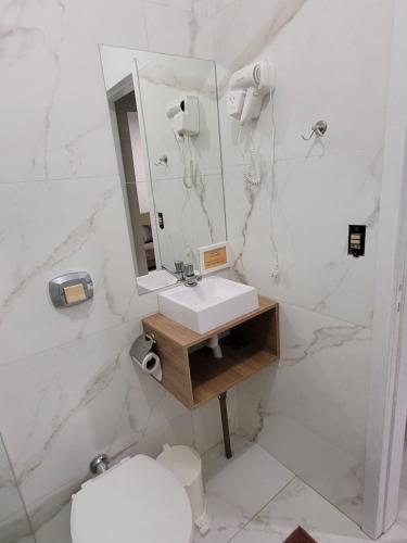 a bathroom with a sink and a mirror and a toilet at Novo Lar Itapema-2 in Itapema