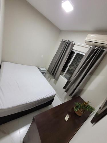 a small bedroom with a bed and a table at Novo Lar Itapema-2 in Itapema