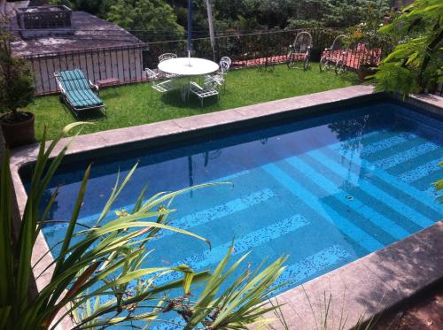 a swimming pool in a yard with a table and chairs at La Casa del Sol - Cuernavaca in Cuernavaca
