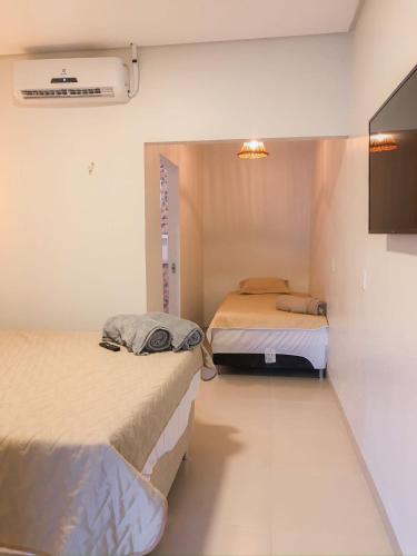 a room with two beds and a tv on the wall at Chalés da Chapada in Carolina