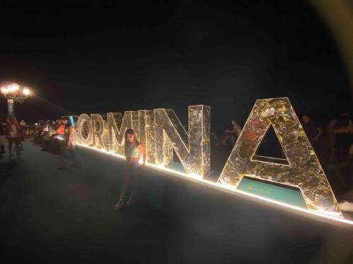 a person standing in front of a sign with lights at Casa Vacanza Giardini Naxos Taormina MIRANAXOS in Giardini Naxos