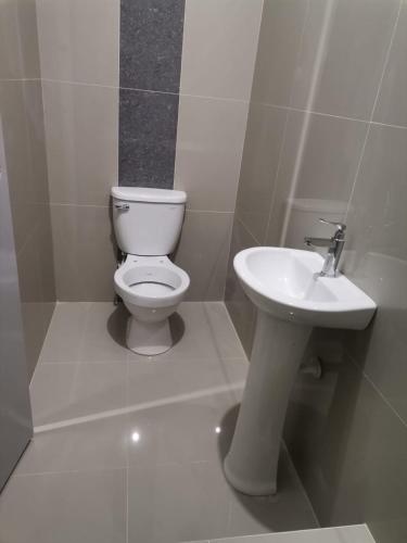 a white bathroom with a toilet and a sink at Hotel JK in Pucallpa