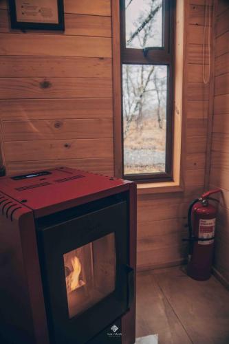 a woodburning stove in a room with a window at Yuki Yama in Malalcahuello