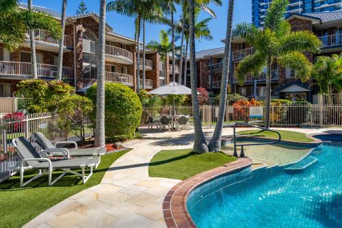 a pool at a resort with chairs and palm trees at Oceanside Cove in Gold Coast