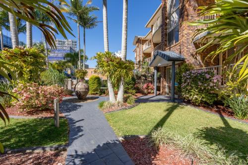 a walkway in front of a house with palm trees at Oceanside Cove in Gold Coast