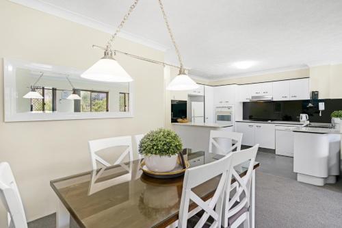 a kitchen and dining room with a glass table and white chairs at Oceanside Cove in Gold Coast