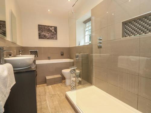 Un baño con lavabo, inodoro y ducha. en Gweek House, en Helston