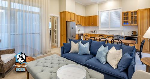 Una sala de estar con un sofá azul y una cocina. en Seaspray Cottage Holiday Accommodation Victor Harbor, en Victor Harbor