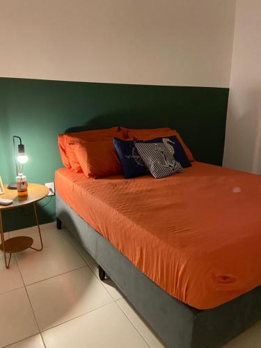 a bedroom with a bed with orange sheets and a green wall at Apartamento a 100 metros da praia no melhor bairro de Bertioga in Bertioga