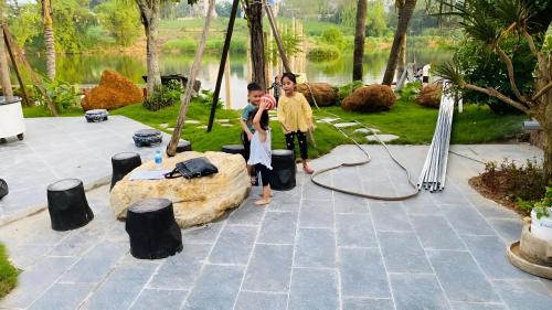 two children standing next to a rock in a garden at Tung Quang Hotel in Cat Ba