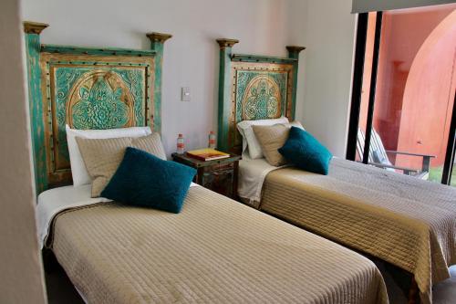 a room with two beds with blue pillows at "San Miguelito" El oasis urbano que necesitas para descansar! pool, gym, tenis in San Miguel de Allende
