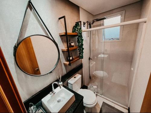 a bathroom with a sink and a mirror and a toilet at Apartamento Luxo Executivo in Bento Gonçalves
