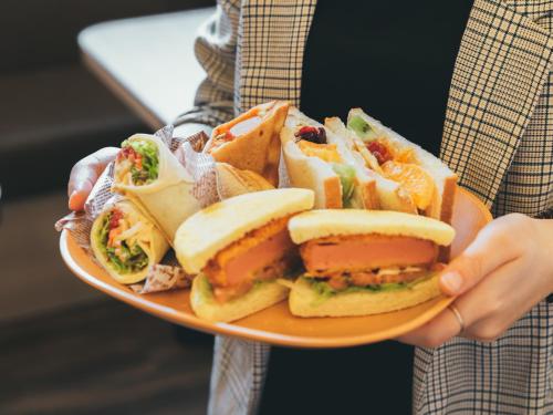 a person is holding a plate of sandwiches at QuintessaHotel KagoshimaTenmonkan Relax&Sleep in Kagoshima