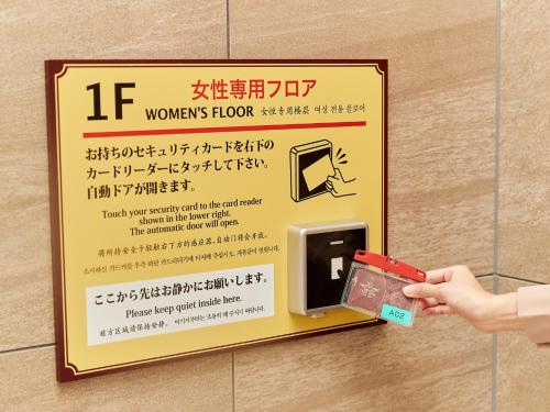 a person holding a phone in front of a sign at Grand Cabin Hotel Naha Oroku for Women / Vacation STAY 62324 in Naha