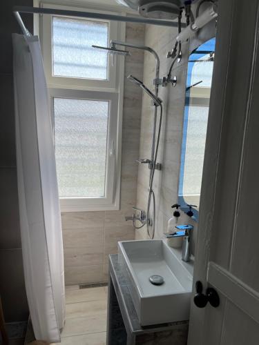 een badkamer met een wastafel, een douche en een raam bij 1922 Historic House in Kavala